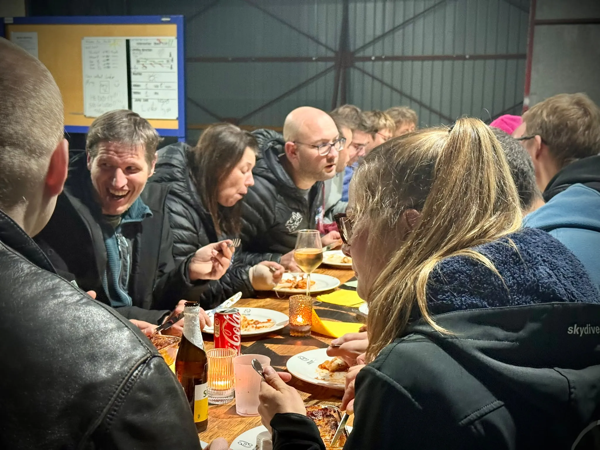 People chatting and eating along a dinner table by candlelight